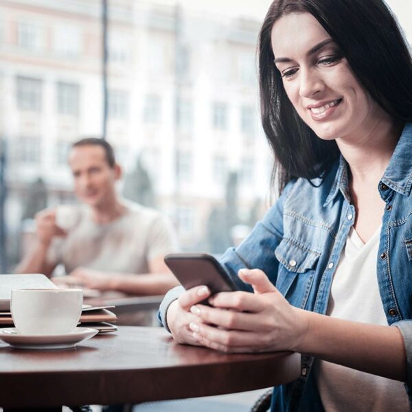 Woman Looking At Smart Phone In Cafe